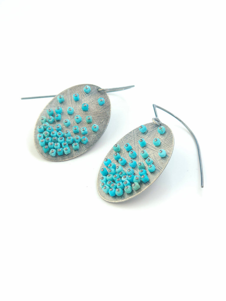 Pair of earrings with turquoise beads on a white background