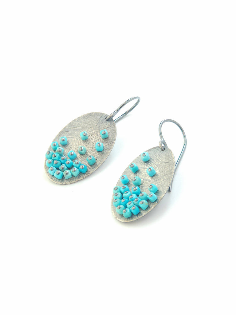 Pair of earrings with turquoise bead embellishments on a white background